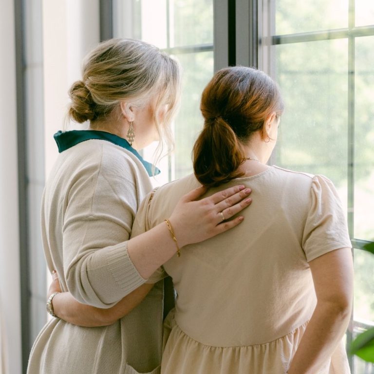 Lilli Heinze Beratung Zwei Frauen stehen nebeneinander und schauen aus einem Fenster.